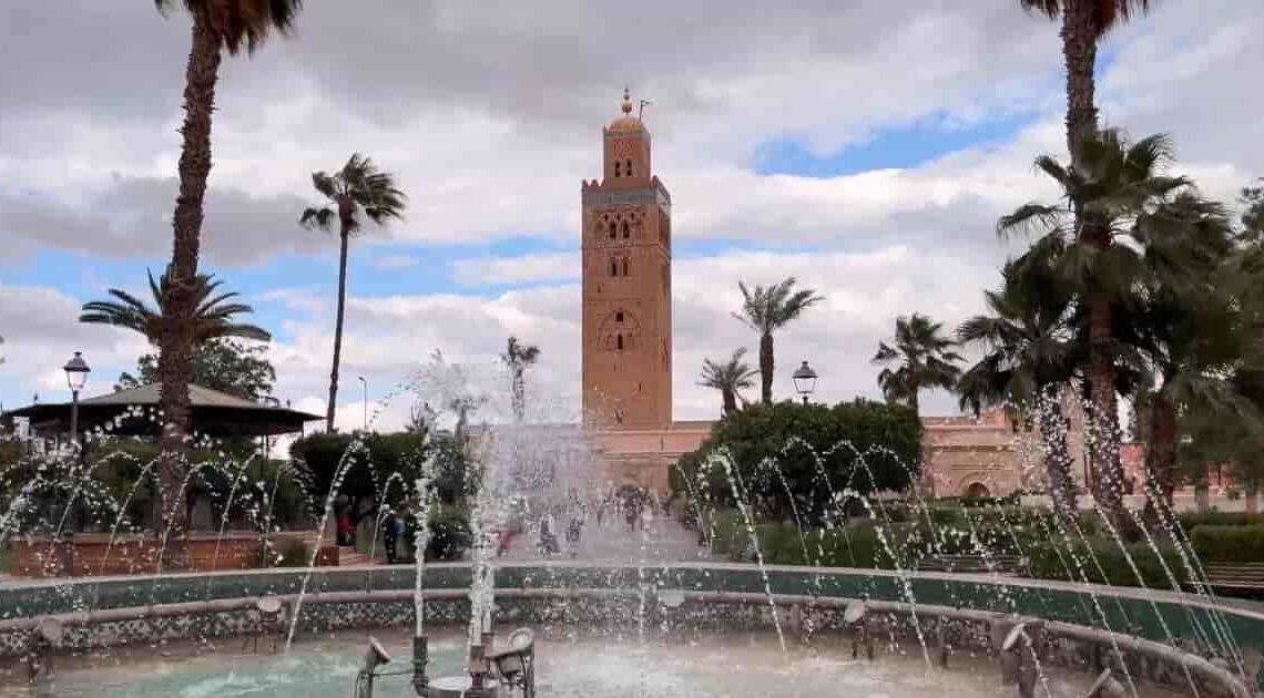 Koutoubia Mosque in Marrakech with fountain and palm trees in the foreground