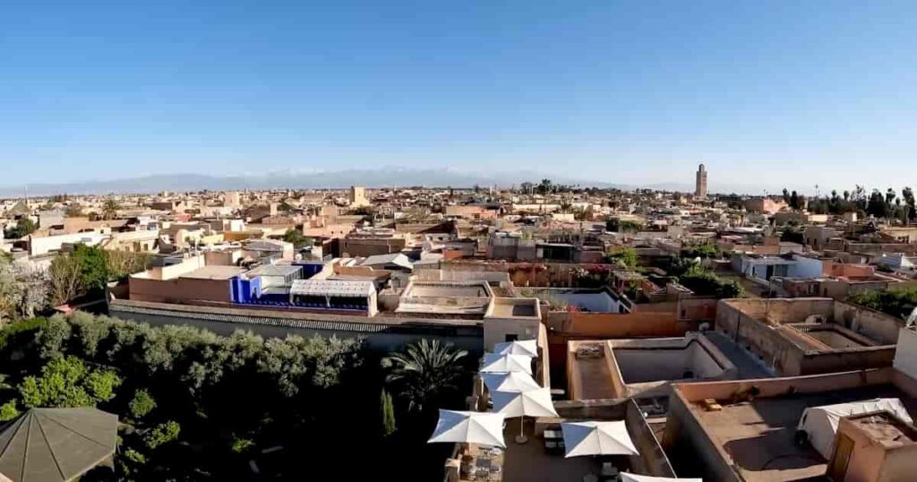 Panoramablick über die Medina von Marrakesch mit Koutoubia Moschee und Atlasgebirge im Hintergrund