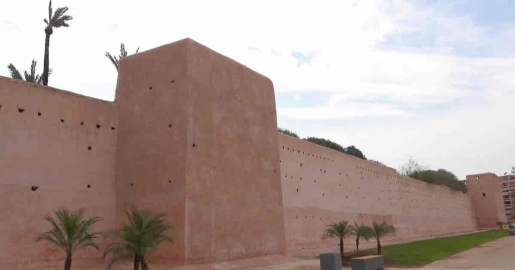 Stadtmauern von Marrakesch aus rotem Lehm entlang der Medina mit Palmen im Vordergrund