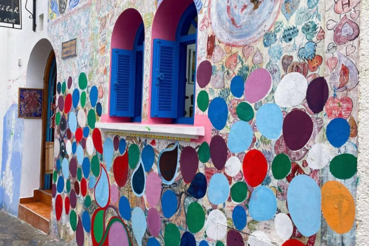 Vibrant mural with colorful circles, faces, and handwritten hearts on a creative wall in Asilah.