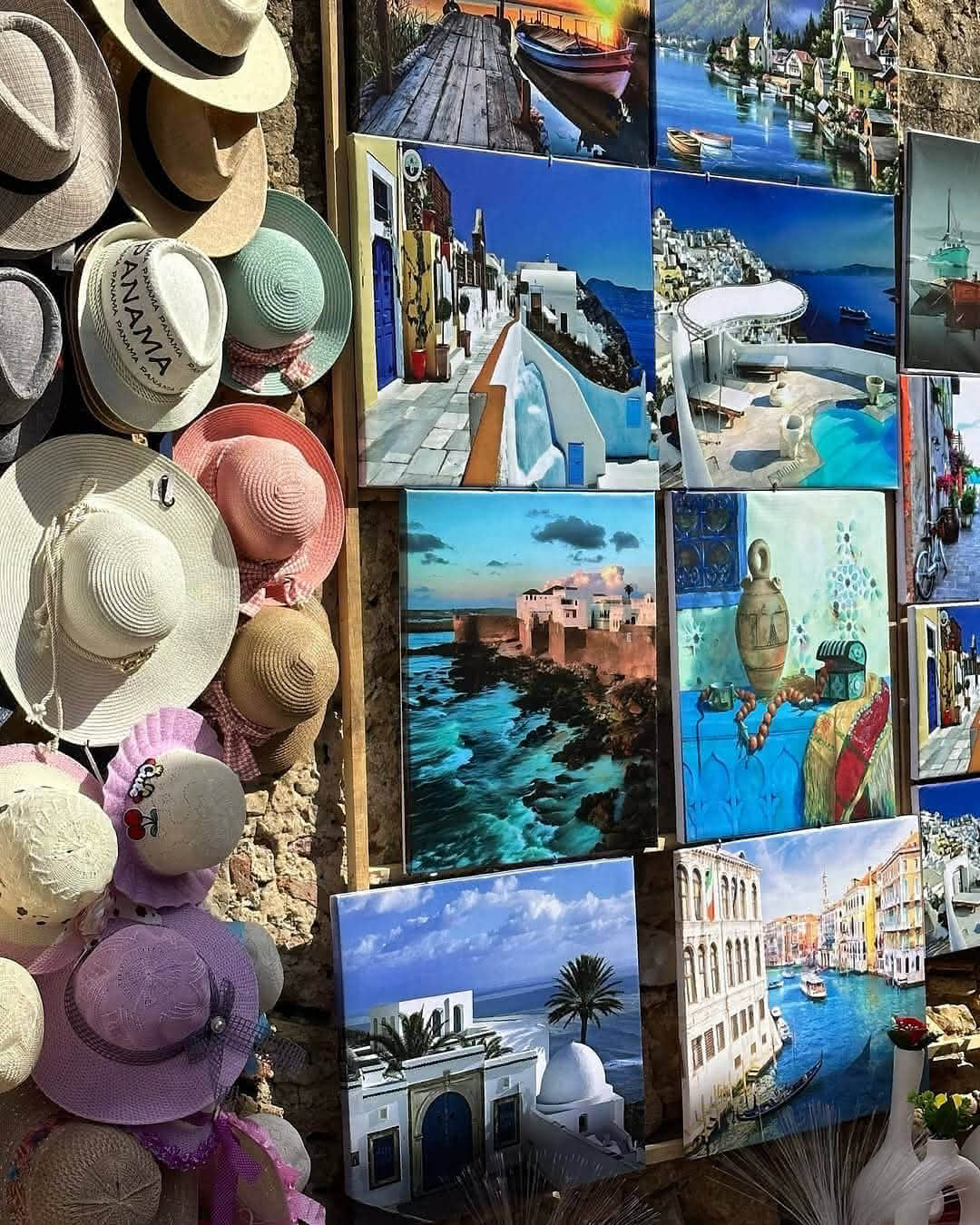 Display of handmade sun hats and colorful paintings in an Asilah street market on a Tangier day trip