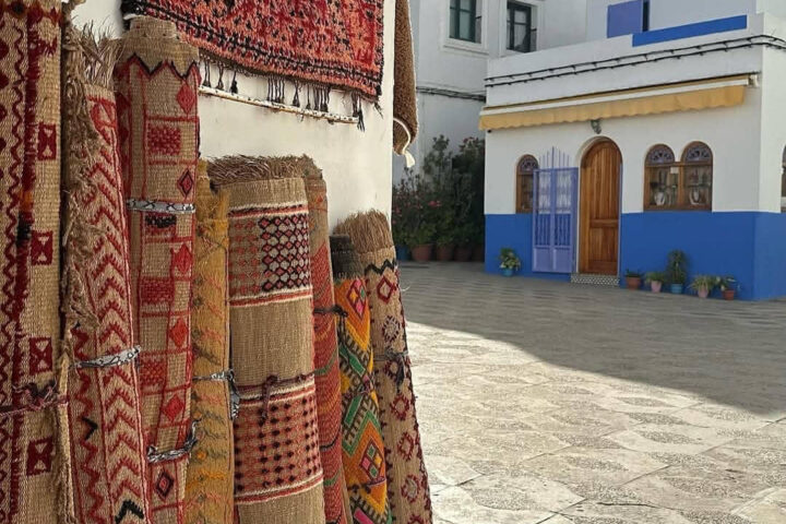 Traditional Moroccan Berber rugs displayed in a colorful street market in Asilah during a Tangier shore excursion.
