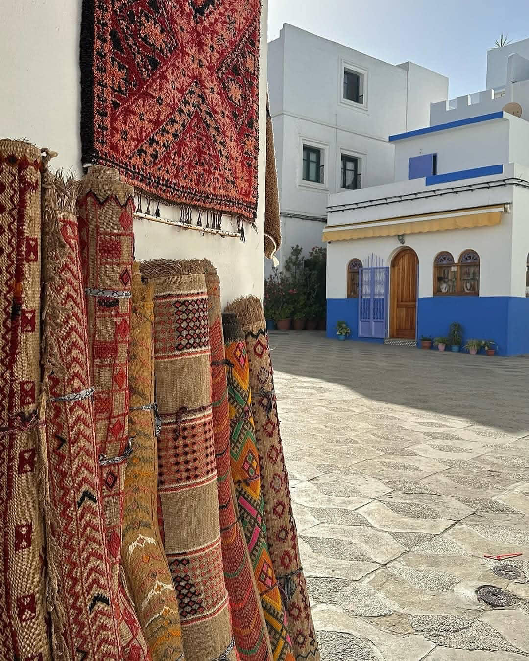 Traditional Moroccan Berber rugs displayed in a colorful street market in Asilah during a Tangier shore excursion.