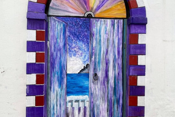 Artistic mural of a painted doorway revealing an ocean view in Asilah’s medina.
