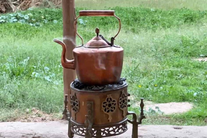Traditioneller Wasserkocher aus Kupfer auf Kohleofen zur Zubereitung von marokkanischem Minztee im Freien