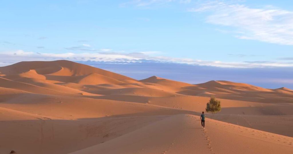 Weite Dünenlandschaft der Merzouga Wüste mit Wanderer in Erg Chebbi