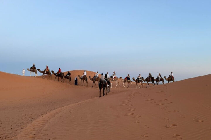 Kamelkarawane in der Merzouga Wüste mit Touristen auf Dromedaren