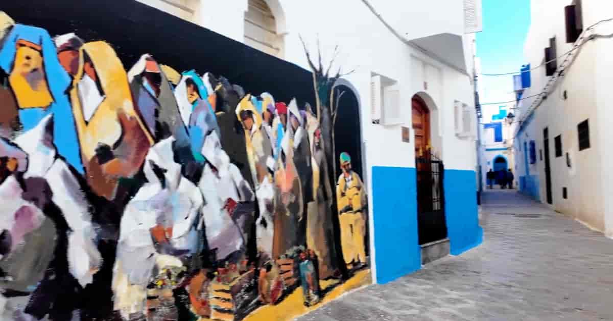 Medina von Asilah mit Wandmalerei und traditionellen Häusern Asilah Medina Gasse Wandmalerei Marokko weiße Häuser blaue Türen