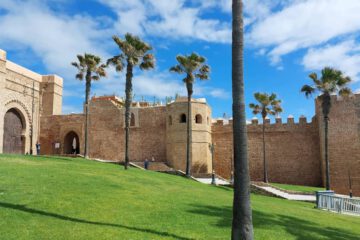 Die historische Festungsanlage der Kasbah der Udayas in Rabat mit ihren hohen Mauern und Palmen unter blauem Himmel.