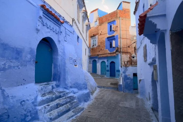 Blue-painted alleyway in Chefchaouen with pots and arched doors
