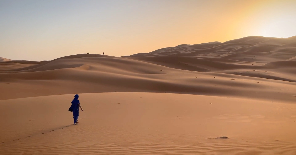 Independent Traveler Exploring Morocco’s Sahara Desert at Sunrise Independent traveler overlooking the vast Sahara Desert at sunrise, reflecting modern travel freedom