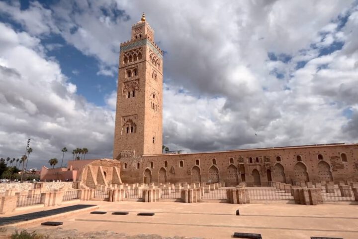 Koutoubia Mosque with palm trees and red city walls in Marrakesh