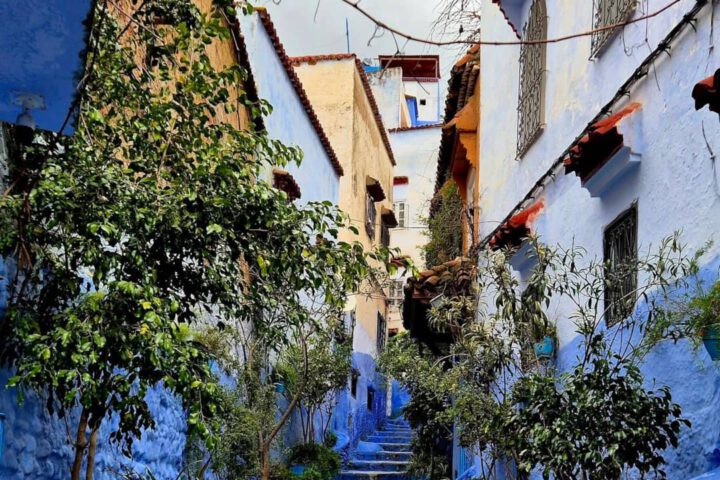 Traditional blue-washed facade and ornate wooden door in the Medina of Chefchaouen, Morocco.