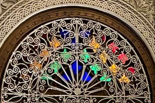 Close‑up of a Moroccan window: carved plaster, decorative wooden elements and ornate metal window grilles with warm light
