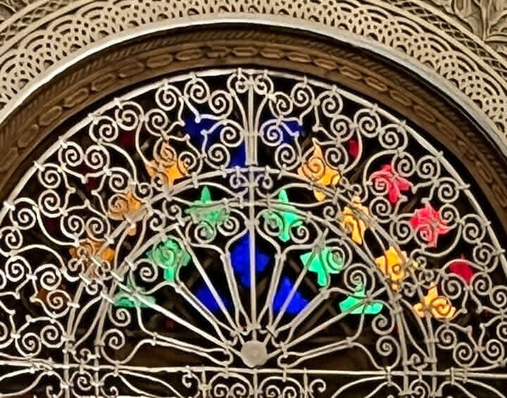 Close‑up of a Moroccan window: carved plaster, decorative wooden elements and ornate metal window grilles with warm light