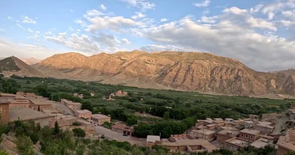 Panoramablick auf das Aït Bouguemez Tal im Hohen Atlas mit traditionellen Berberhäusern, grünen Feldern und umliegenden Bergen