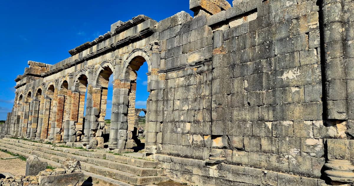 Roman basilica ruins at Volubilis with standing arches and stone columns.