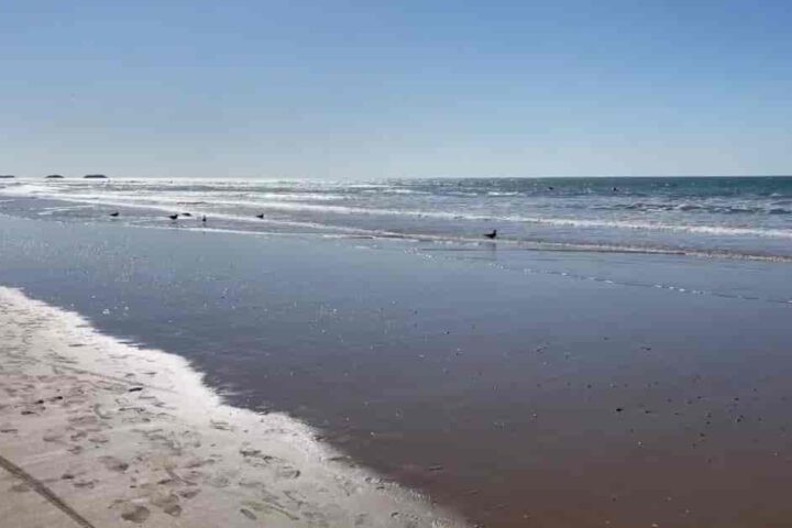 Weiter Sandstrand in Agadir mit sanften Wellen des Atlantiks und ruhiger Küstenlandschaft
