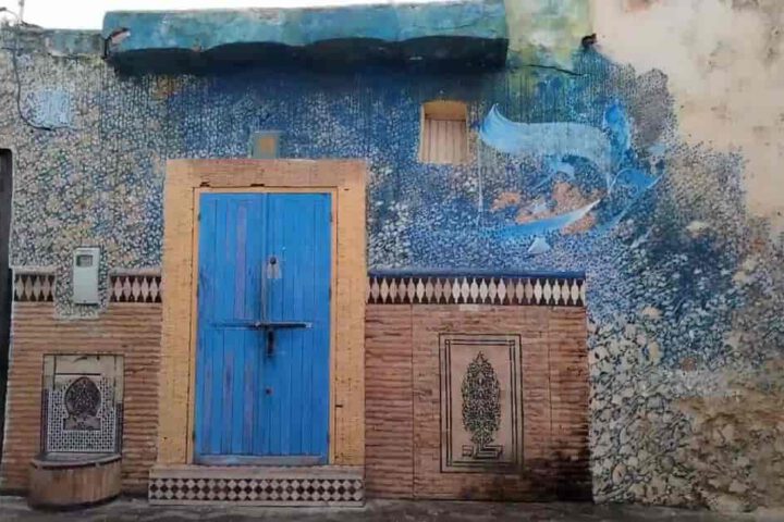 Blue door and artistic mural in Asilah medina showcasing colorful street art in Morocco